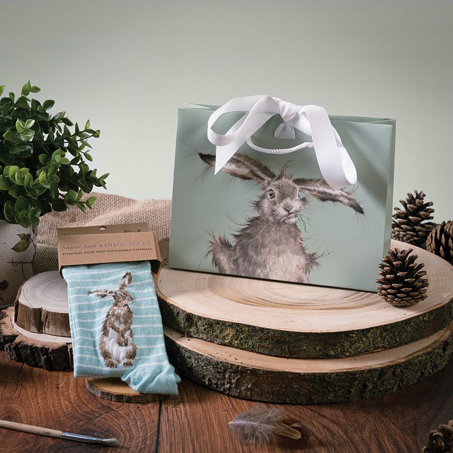 Gift bag with rabbit design and matching socks on a wooden surface with decorative elements.