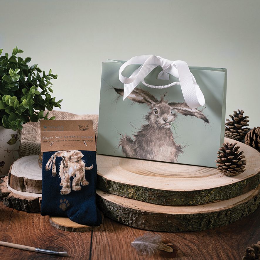Gift bag with a rabbit design on a wooden surface with decorative elements.