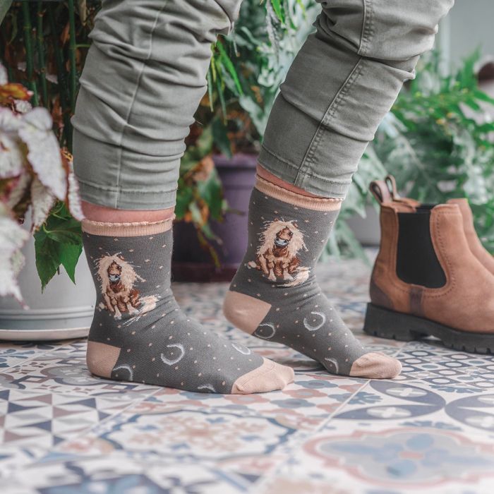 Person wearing socks with horse designs on a patterned floor.