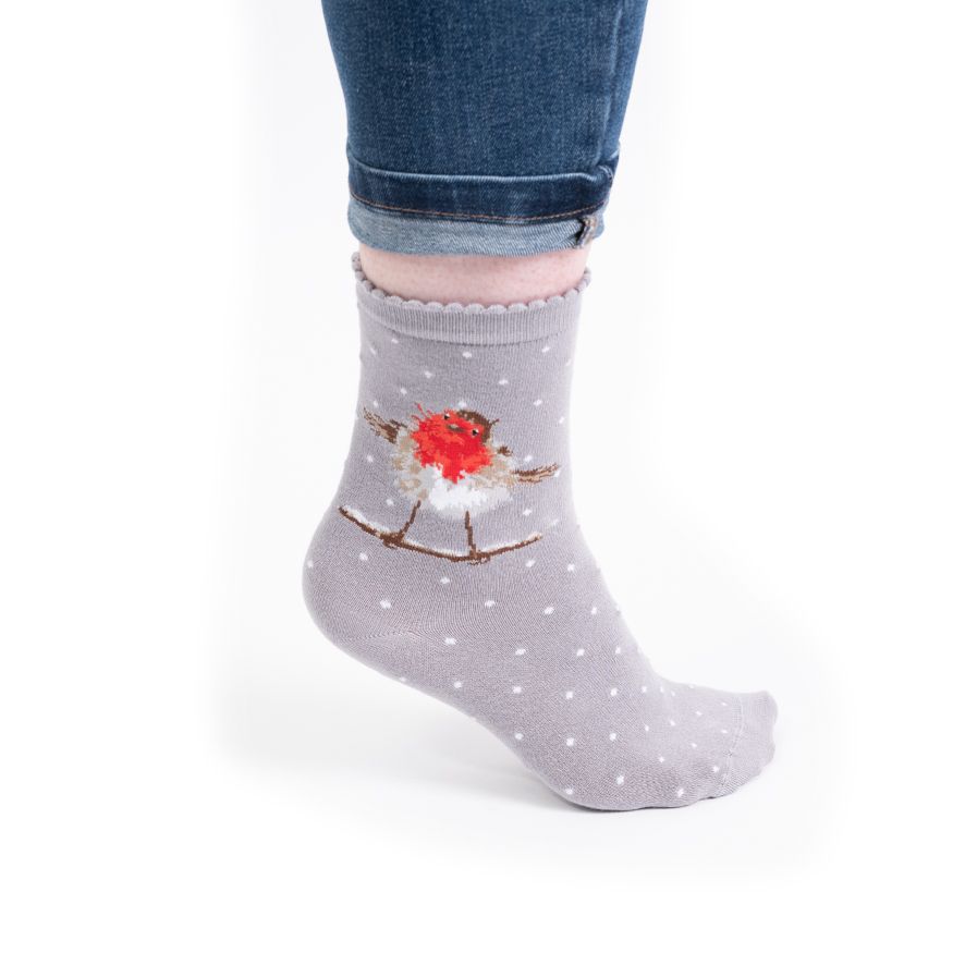 A person's foot wearing a light gray ankle sock with a robin bird graphic and white polka dots, paired with blue jeans against a white background.