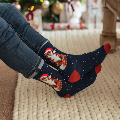 Person wearing festive socks with dog designs in a cozy living room setting.
